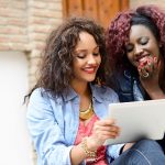 Two beautiful girls with tablet computer in urban backgrund